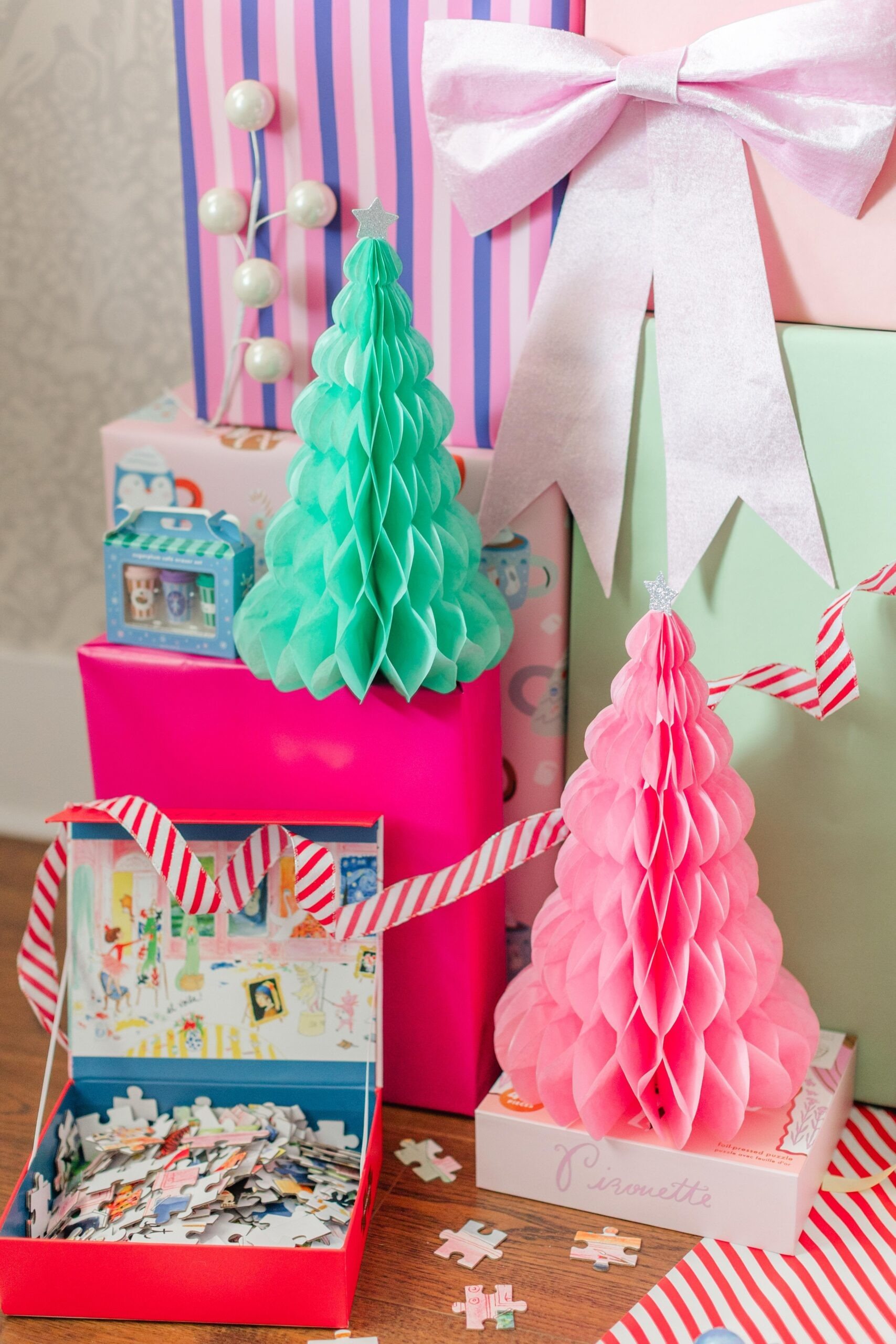 A Jollity & Co holiday gift stack with pink and mint honeycomb trees and an open puzzle