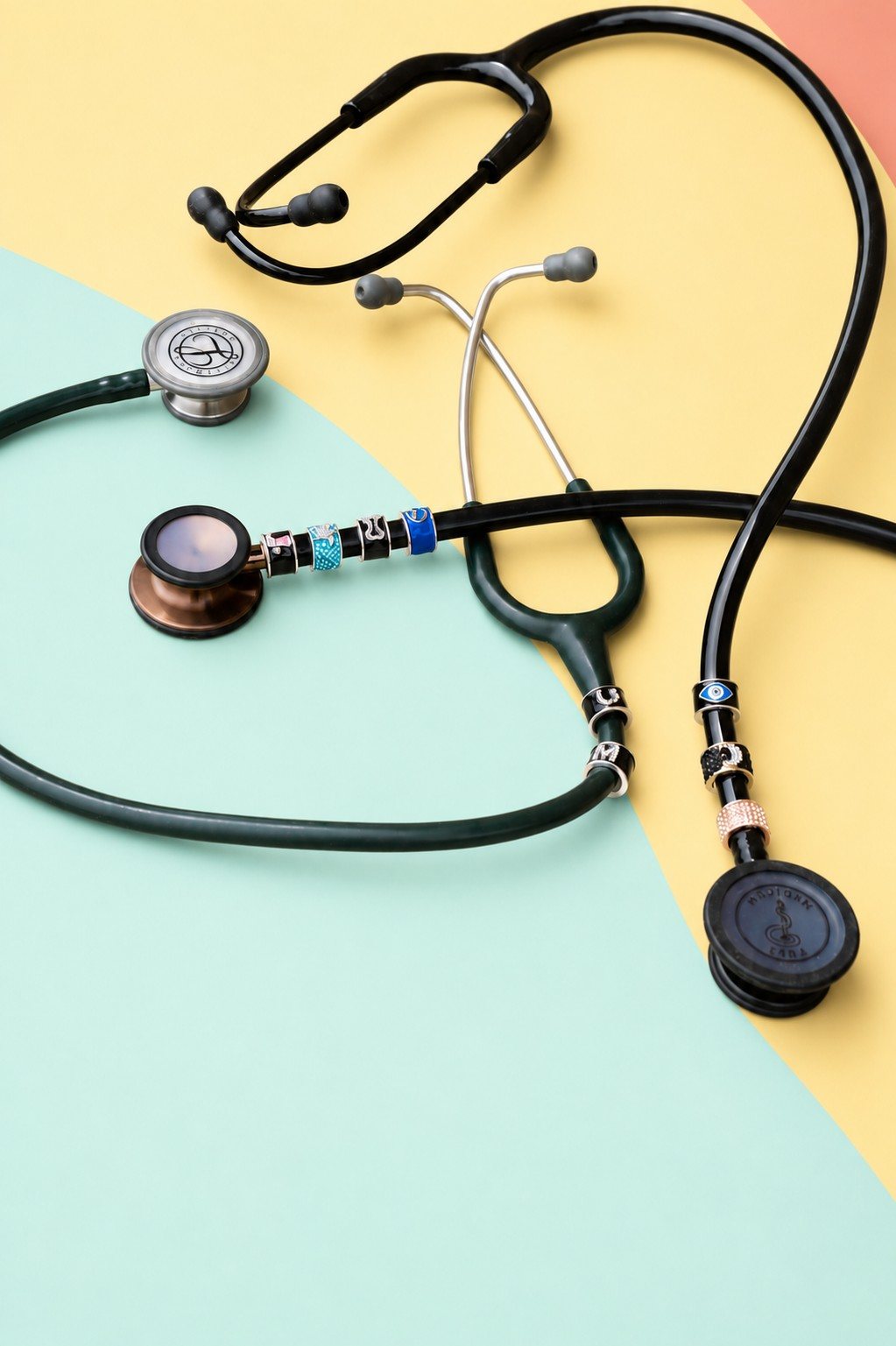 Charmedbling stethoscope charms on pastel paper in soft palm-leaf shadow